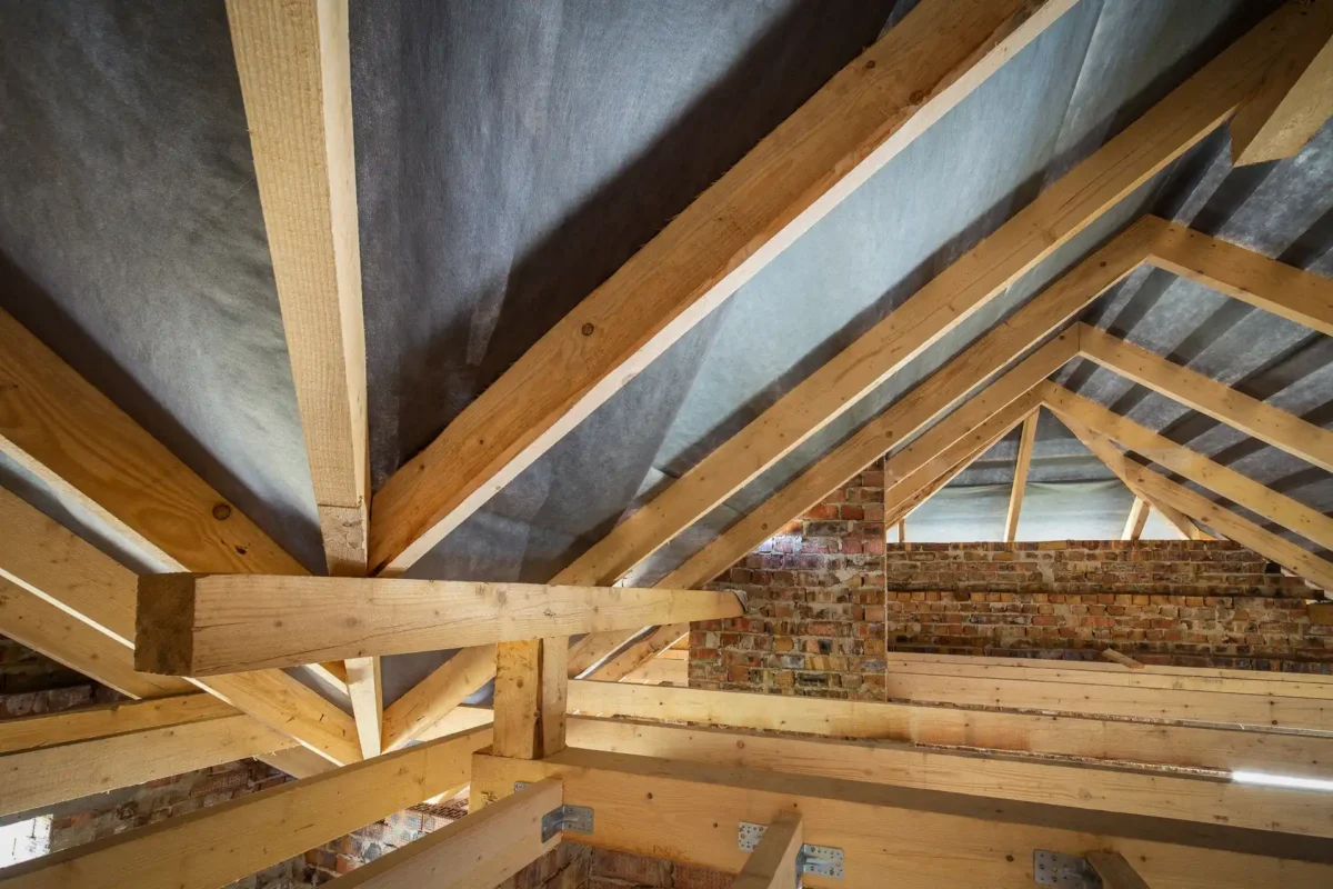 Drewniana konstrukcja więźby dachowej połączona ze ścianą szczytową z cegły