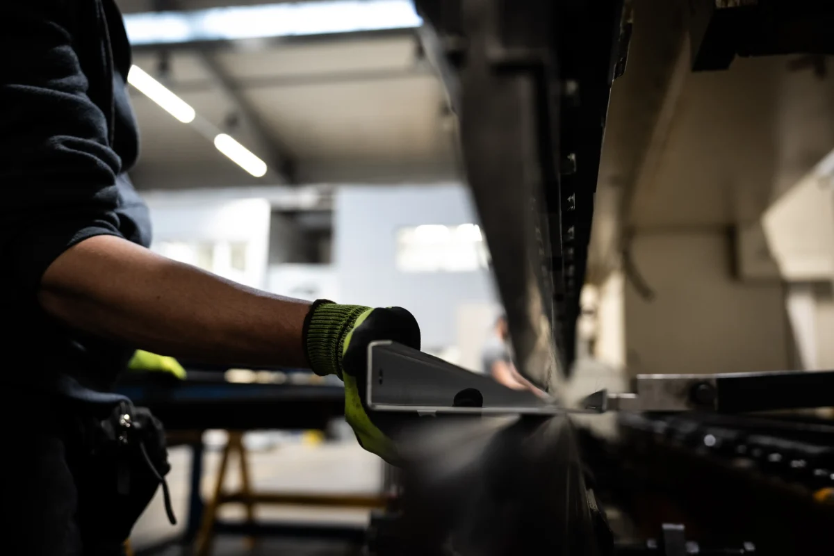 Operator ręcznie prowadzi długi profil blachy w prasie krawędziowej