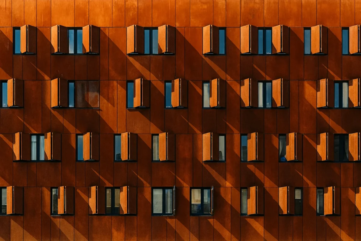 Fasada budynku z paneli ze stali corten z szeregiem okien i ruchomych osłon